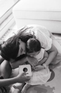A black and white image of a mother cuddling with her one year old daughter on the floor of their apartment in Cambridge, Massachusetts. Captured on 35mm film.