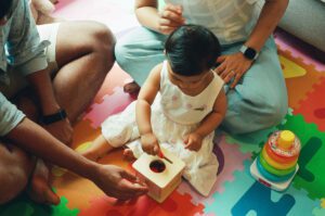 A closeup image of a mother and father playing with their one year old daughter on a colorful play mat on the floor of their apartment in Cambridge, Massachusetts. Captured on 35mm film.